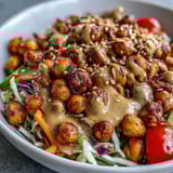 Overhead view of a nutritious Peanut Chickpea Protein Bowl served over brown rice, topped with edamame, cherry tomatoes, and chopped peanuts.