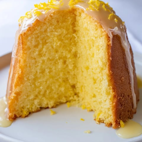 Golden-brown Lemon Pound Cake slice, glistening with lemon glaze, ready for a delightful bite.