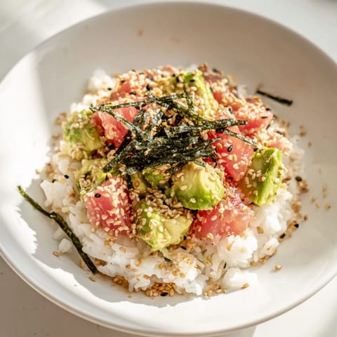 Warm jasmine rice topped with flaky tuna, creamy avocado, crisp cucumber, and toasted sesame seeds in a vibrant bowl.
