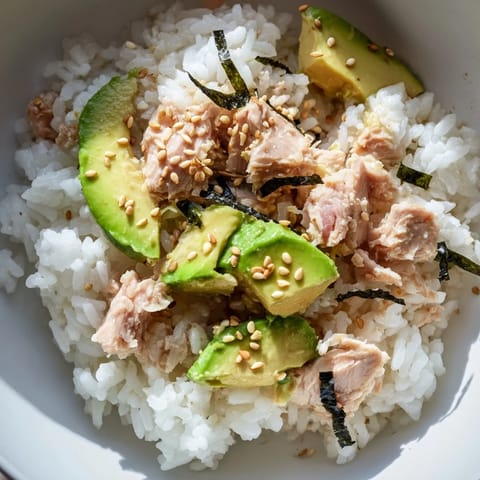 A quick Tuna Avocado Rice Bowl featuring tender tuna, diced avocado, and crunchy cucumber with a drizzle of sesame-soy dressing.