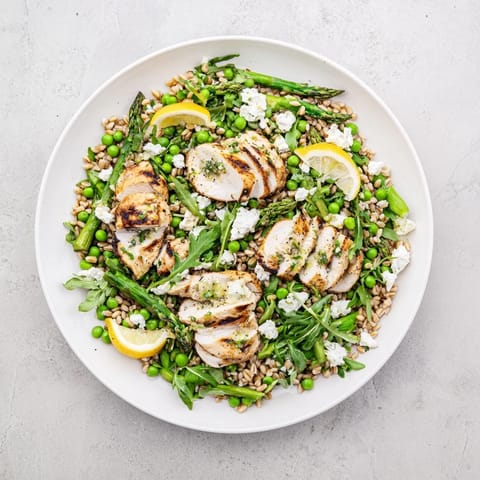 Sliced grilled chicken, tender farro, blanched asparagus, and peas tossed with arugula in a bright lemon vinaigrette for a refreshing warm spring farro chicken salad.  