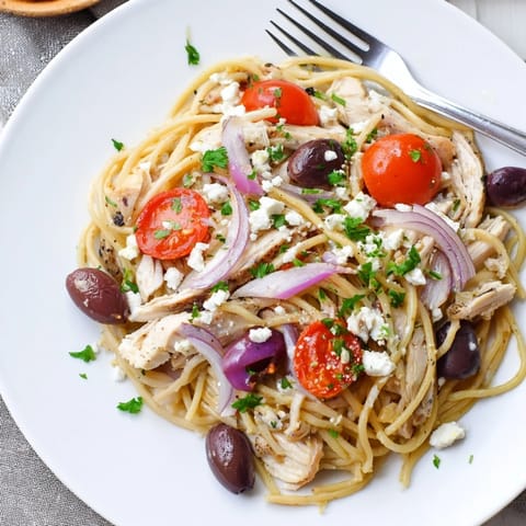 A close-up of Greek Chicken Spaghetti featuring tender pasta, garlic-onion sauté, parsley, and tangy feta.