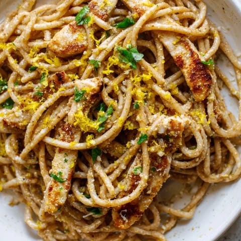 Freshly grated Parmesan and lemon wedges accompany this savory Brown Butter Lemon Chicken Pasta, showcasing tender chicken and glossy sauce.
