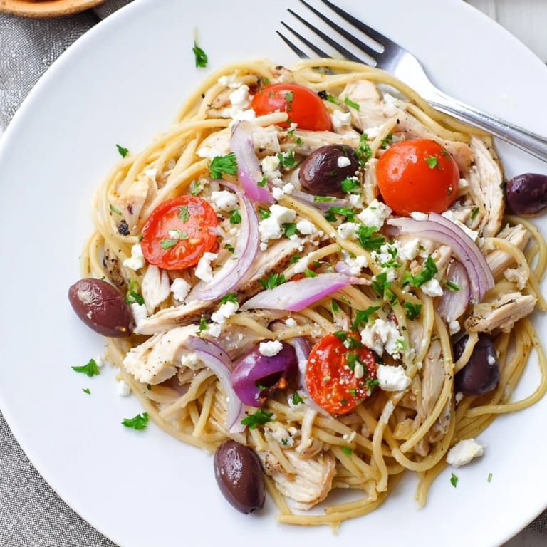 A close-up of Greek Chicken Spaghetti featuring tender pasta, garlic-onion sauté, parsley, and tangy feta.