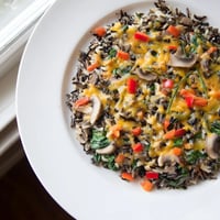 Steaming hot wild rice casserole, showcasing earthy mushrooms and baked vegetables, ready to serve.