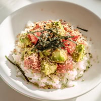 Warm jasmine rice topped with flaky tuna, creamy avocado, crisp cucumber, and toasted sesame seeds in a vibrant bowl.