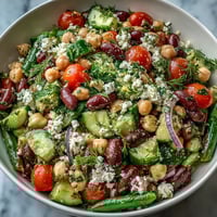 Bright Greek Bean Salad with feta and olives sits on a platter, marinated beans glistening in lemon-oregano dressing.