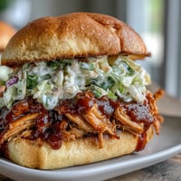 Pulled BBQ chicken sandwiches with tender, saucy chicken piled high on soft brioche buns, perfect for summer cookouts.  